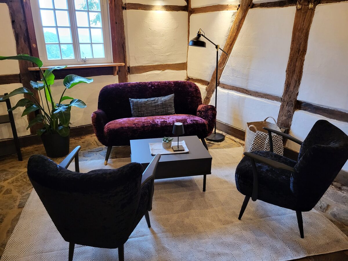 Gemütliche Sitzecke im Café des Mühlenhofs: Samtsofa und Sessel in einem historischen Fachwerkraum.