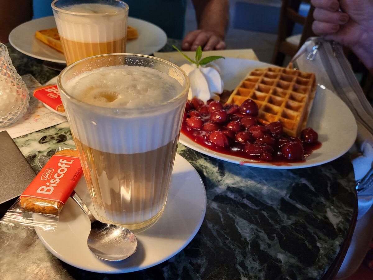 Belgische Waffel mit heißen Kirschen und Latte Macchiato im Café.