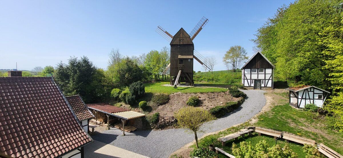 Das Gelände des Mühlenhofs Breckerfeld im Frühling: die Bockwindmühle auf einem grünen Hügel, umgeben von Fachwerkgebäuden.